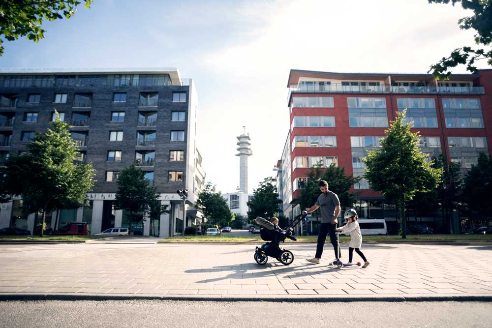 Pappa som går med sitt barn utanför lägenhetshus